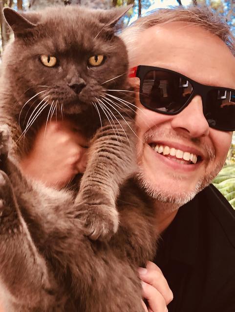 Smokie, a british shorthair cat, looking at the camera and Florian holding it.